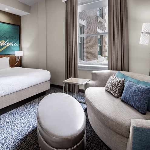 bed and sofa with pillows in hotel room